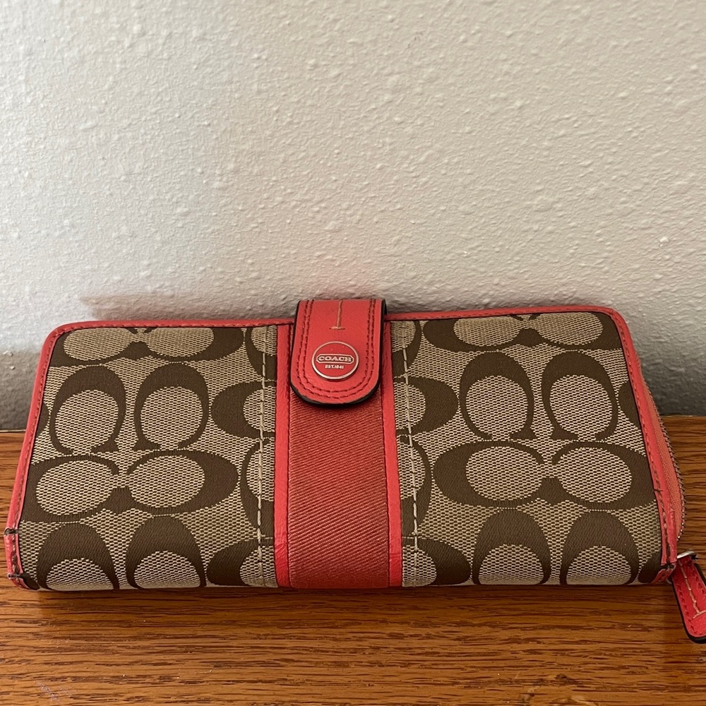 Coach signature canvas wallet with pink leather trim and a snap closure.